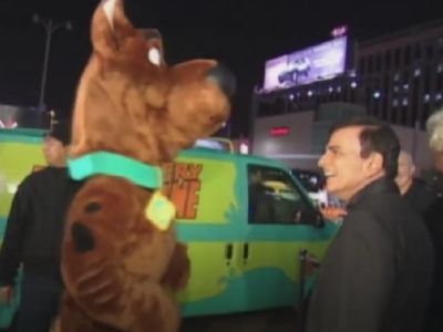 Human in Scooby costume is dancing whereas, Casey Kasam is smiling looking at him.